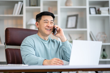 Smiling asian man holding smartphone sitting in office. Digital technology applications and solutions for business development. Copy space