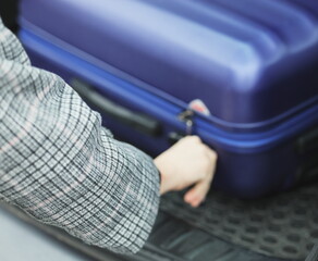 the girl takes out a suitcase from the car, the woman closes the suitcase, traveling by car,...