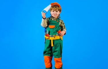 Builder boy in safety helmet and toolbelt with saw. Child in builder uniform with tool belt. Tools for building. Little kid repairman with saw. Work with repair tools. Little boy construction worker.