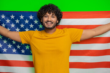 Young indian man waving and wrapping in American USA flag, celebrating, human rights and freedoms. Vote, president election. Independence day. Hindu guy patriot isolated on green chroma key background