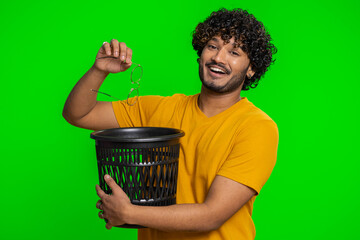 Indian bearded man taking off throwing out glasses into bin after medical vision laser treatment therapy surgery looking smiling at camera. Handsome hindu guy isolated alone on chroma key background
