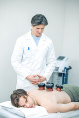 Doctor putting medical cups on his patients back