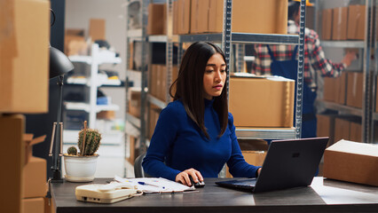 Young adult working on retail stock orders in depot, checking distribution and shipment on...