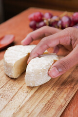 hand pick Camembert cheese on table 