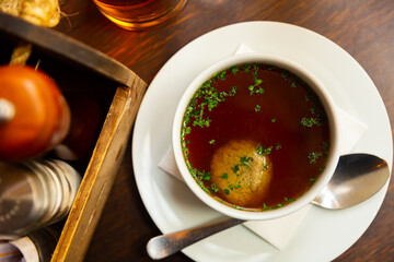Just cooked portion of beef soup with liver dumplings served on table with spoon.