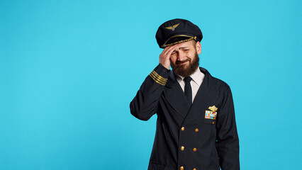 Sick airplane pilot suffering from headache, being worried about painful migraine and feeling ill. Professional airline captain being unhappy and in pain, feeling pressure rubbing temples. - obrazy, fototapety, plakaty