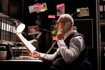 Private detective talking at landline phone with remote inspector, discussing criminal...