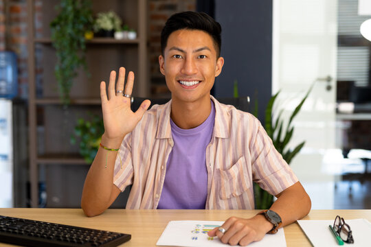 Portrait of happy asian casual businessman making video call smiling and waving