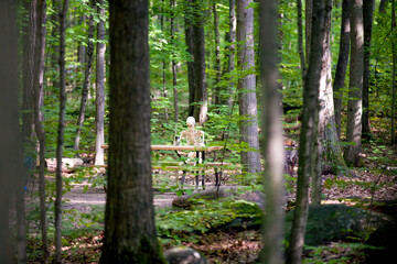 A skeleton spending some time in a campground sitting at a picnic table.