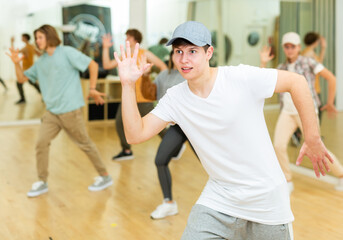 Fototapeta na wymiar Emotional teen b-boy dancing with group of friends in dance studio. Hip-hop generation.