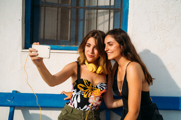 Happy girlfriends taking selfie on smartphone