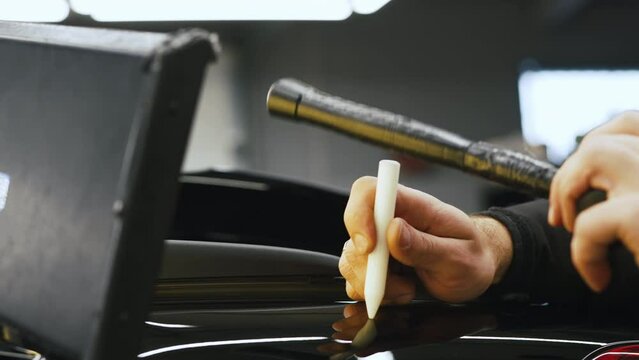 Using a hammer and a PDR tool to repair a dent on a car bodywork. High quality 4k footage