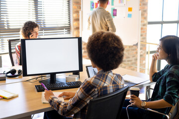 Two diverse female creatives at computer with copy space on screen, having video call in busy office