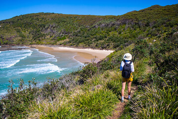 Girl in a hat walks next to stunning hidden third beach (cove) in Hat Head National Park, Korogoro...