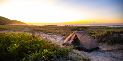 pretty girl camping in the tent on the sand dunes in new south wales, australia, sleeping in the...