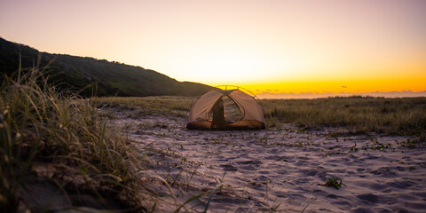 pretty girl camping in the tent on the sand dunes in new south wales, australia, sleeping in the tent on australian beach in front of pacific ocean, transparent tent on the beach