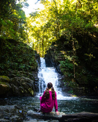Beautiful girl sits and enjoys view of stunning waterfall - Casuarina Falls in Dorrigo National Park, Waterfall Way, NSW, Australia