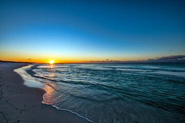 Sunrise on calm shoreline at the ocean.