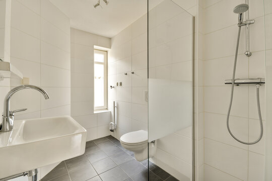 a white bathroom with black tile flooring and walls that have been painted in the same color as they appear