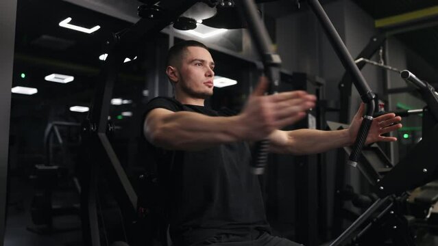 Fitness dedication, Bench press, Cable exercises. Well-toned, handsome man focuses on arm and chest development by using workout machine at gym.