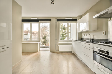 Fototapeta na wymiar a kitchen with wood flooring and white cabinets in the middle of the room, there is a large window that looks out into