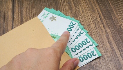 Hand pointing finger at bunch of rupiah money banknotes