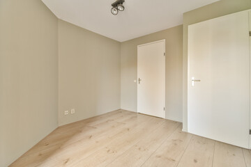 an empty room with wood floors and white doors in the corner, looking towards the entrance to the living room