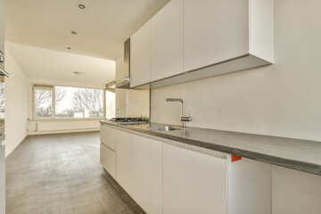 a kitchen with white cabinets and gray counter tops on the counters in front of the sink is visible to the right