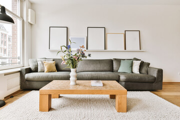 some flowers in a vase on a coffee table next to a gray couch with white and green throw pillows...