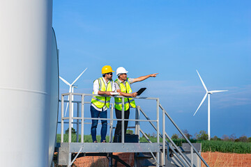 Technician engineers team using tablet computer in wind turbine power generator station in Thailand.