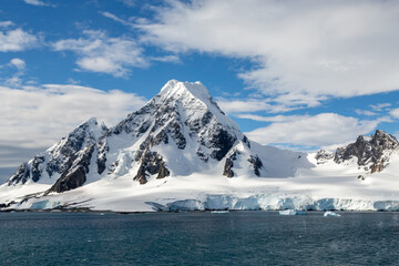 Fototapeta na wymiar Dramatic Slouw Clad Mountains Rising Above the Sea and Glaciers on Antarctic Peninsula 