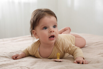 Fototapeta premium Cute little baby with pacifier on bed indoors