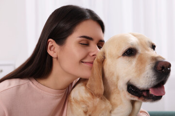 Happy woman with cute Labrador Retriever at home, closeup