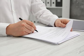Man signing document at wooden table, closeup