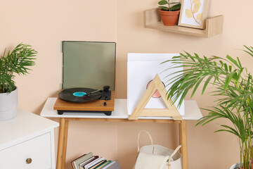 Stylish turntable with vinyl record on wooden table in cozy room