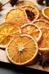 Many dry orange slices and spices on black table, closeup