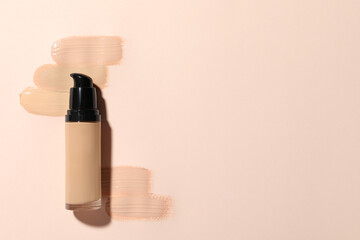 Liquid foundation and swatches on beige background, top view. Space for text