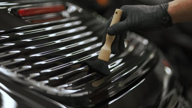 Close shot of a car grill being brushed with a brush by a hand in a black glove. High quality 4k footage