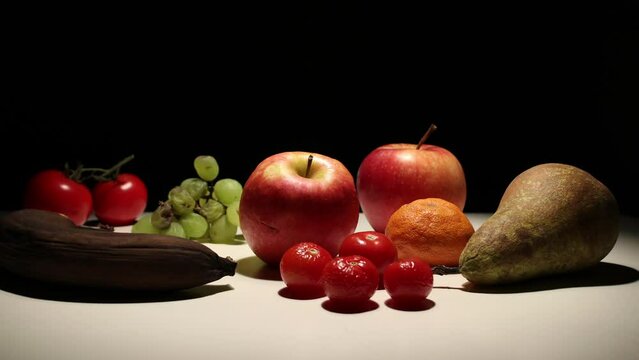 Variety of colorful fruit decomposing, timelapse, black background