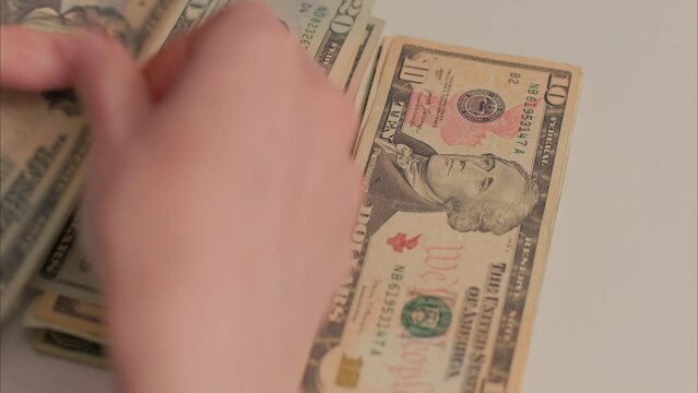 Caucasian Female Hands Stacking And Dividing American Cash Into Two Piles. Shot with ARRI Alexa in ARRIRAW and exported QuickTime Apple ProRes 422 HQ.