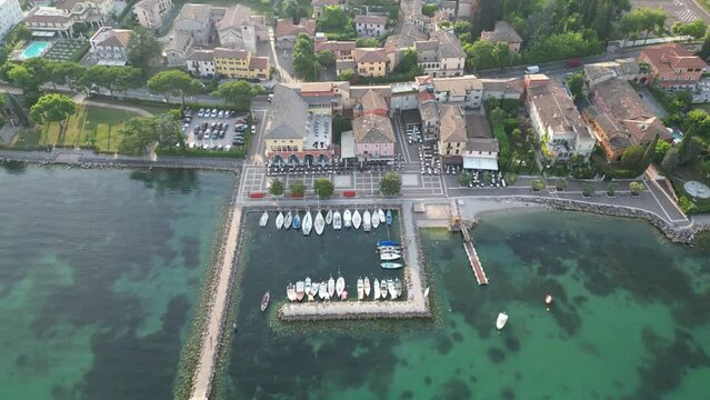 Stunning Turquoise Water By The Cisano Harbour On Lake Garda At Bardolino, Italy. aerial top-down
