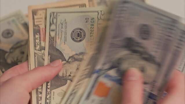 Caucasian Female Hands Counting A Stack of American Cash. Shot with ARRI Alexa in ARRIRAW and exported QuickTime Apple ProRes 422 HQ.