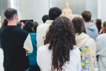 Group of students on excursion visit gallery museum with tour guide, a docent with a tourist adult...