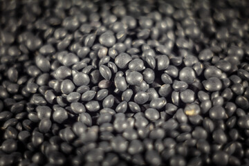 Selective blur on a macro shot of a pile of beluga lentils. Beluga lentils are black lentils of lens culinaris genus, known for their typical bead shape.