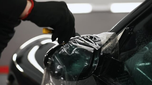 Excess of paint protection film being cut from a car mirror. High quality 4k footage