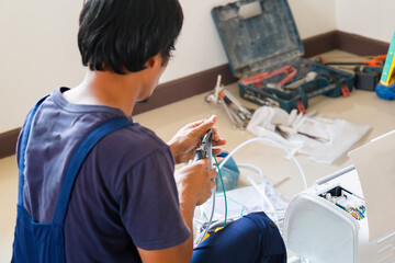 Asian technician man installing air conditioning in client house, Young repairman fixing air conditioner unit, Maintenance and repairing concepts