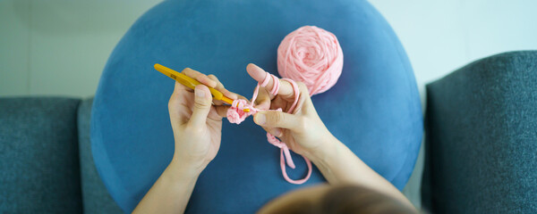 Happy cheerful Asian woman doing a crochet in living room in free time.