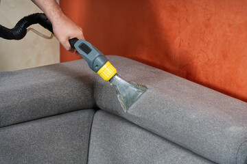 Sofa chemical cleaning with professionally extraction method. Wet textile sofa cleaning. home cleaning service. cleaning sofa with washing suction cleaner closeup.