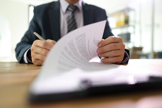 Businessman flips page of contract signing after reading