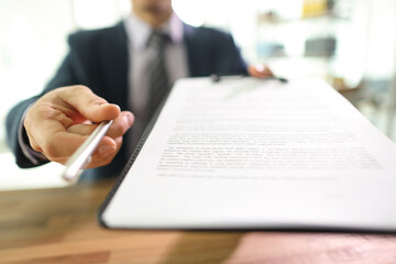 Manager gives contract papers and pen to partner in office